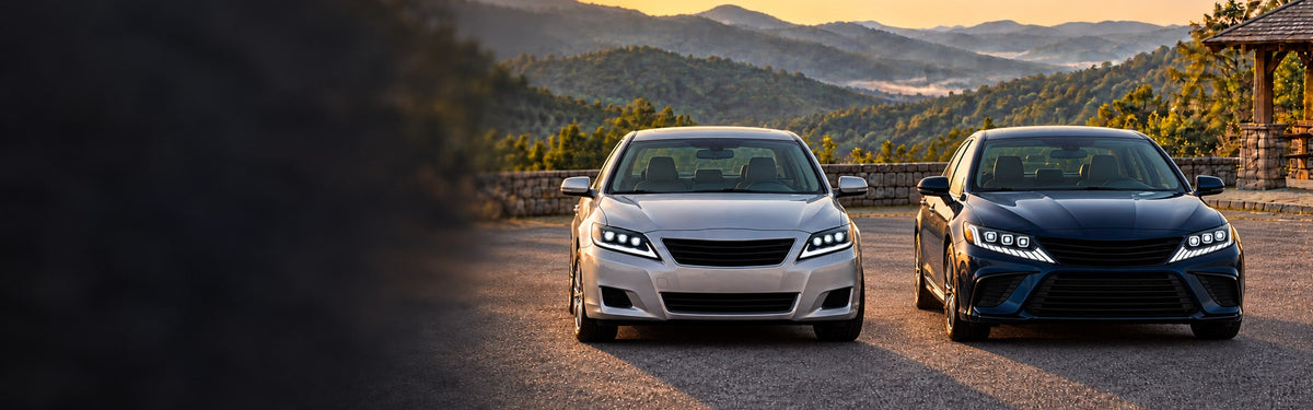 Two Toyota Camry generations with RIGNOX triple projector headlights at a mountain overlook