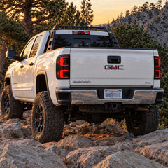 2014-2018 GMC Sierra 1500 & 2015-2019 Sierra 2500HD/3500HD LED Tail Lights Assembly — rear vehicle view with red LED tail lights in off-road setting — T-SIE14-SR