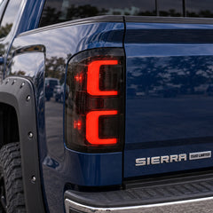 2014-2018 GMC Sierra 1500 & 2015-2019 Sierra 2500HD/3500HD LED Tail Lights Assembly — red running light close-up on blue Sierra — T-SIE14-SR